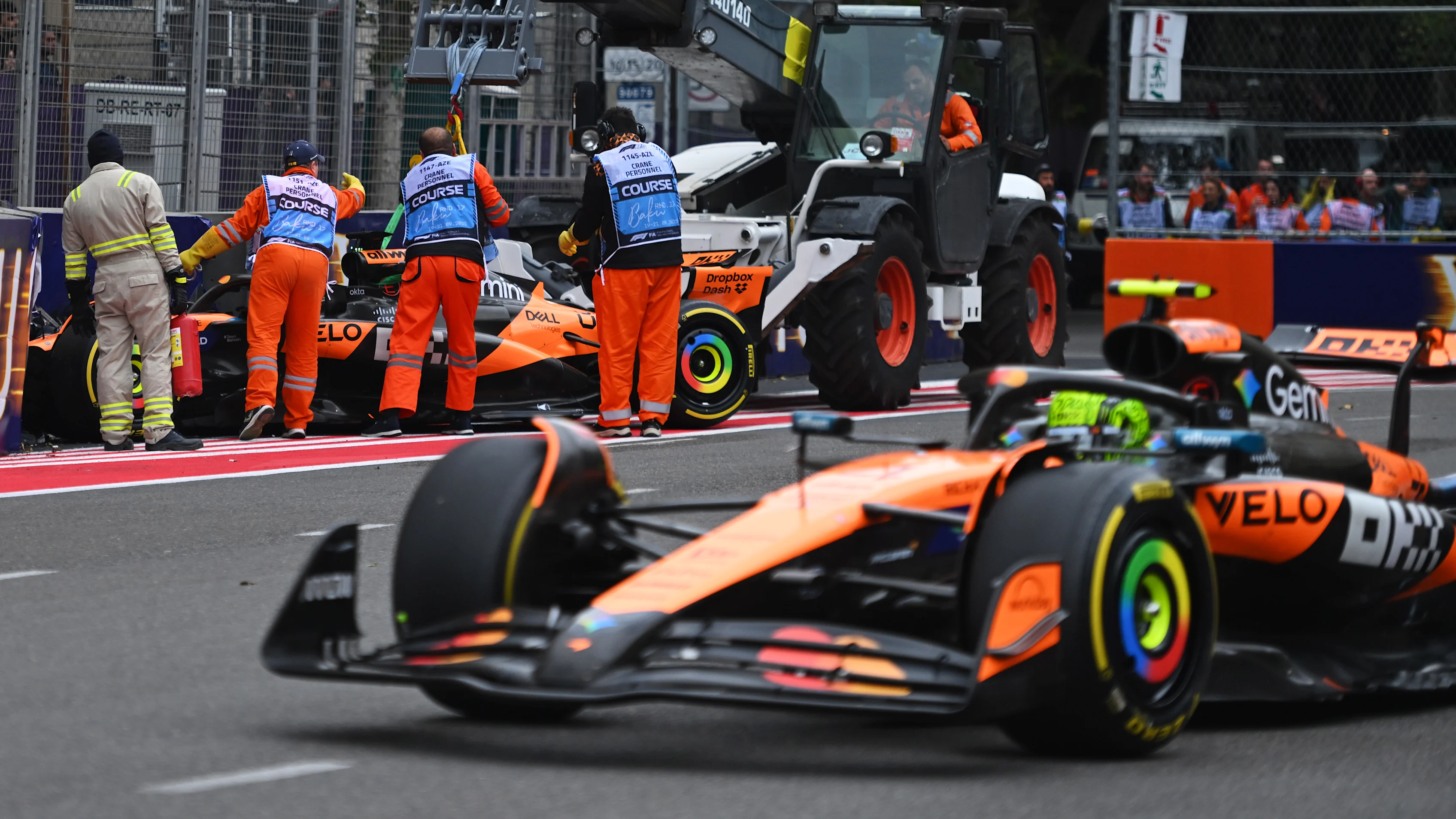 BAKU, AZERBAIJAN - SEPTEMBER 21: Marshals clear away the car of Oscar Piastri of Australia driving the (81) McLaren MCL39 Mercedes, as Lando Norris of Great Britain driving the (4) McLaren MCL39 Mercedes passes them on track during the F1 Grand Prix of Azerbaijan at Baku City Circuit on September 21, 2025 in Baku, Azerbaijan. (Photo by Rudy Carezzevoli/Getty Images)