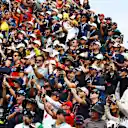 Grandstands are alive with noise, flags, and camera flashes – every fan chasing their own perfect shot. Swipe for more images