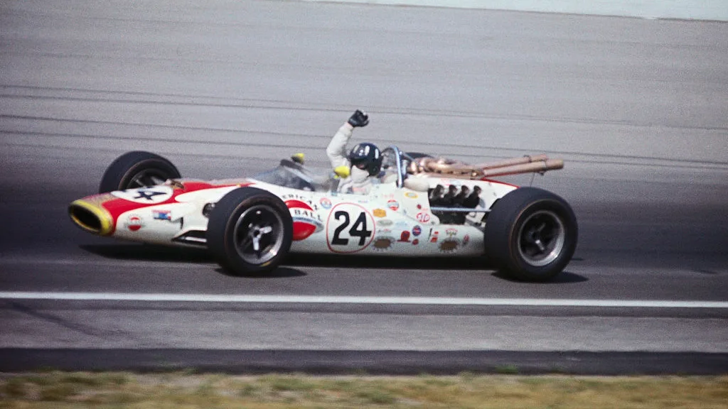 (Légende d'origine) Graham Hill, avec des bras levés dans le signal de victoire, encerclant une piste après avoir gagné